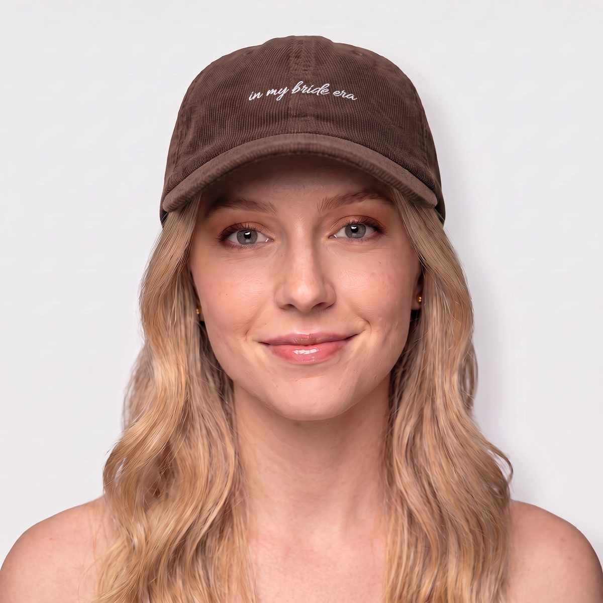 Woman wearing a brown corduroy hat embroidered 'in my bride era' — Taylor Swift Eras-inspired bachelorette cap