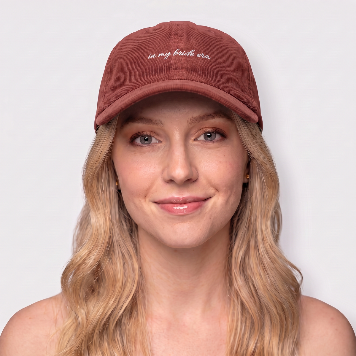Woman wearing a burgundy corduroy hat embroidered 'in my bride era' — Taylor Swift Eras-inspired bachelorette cap

