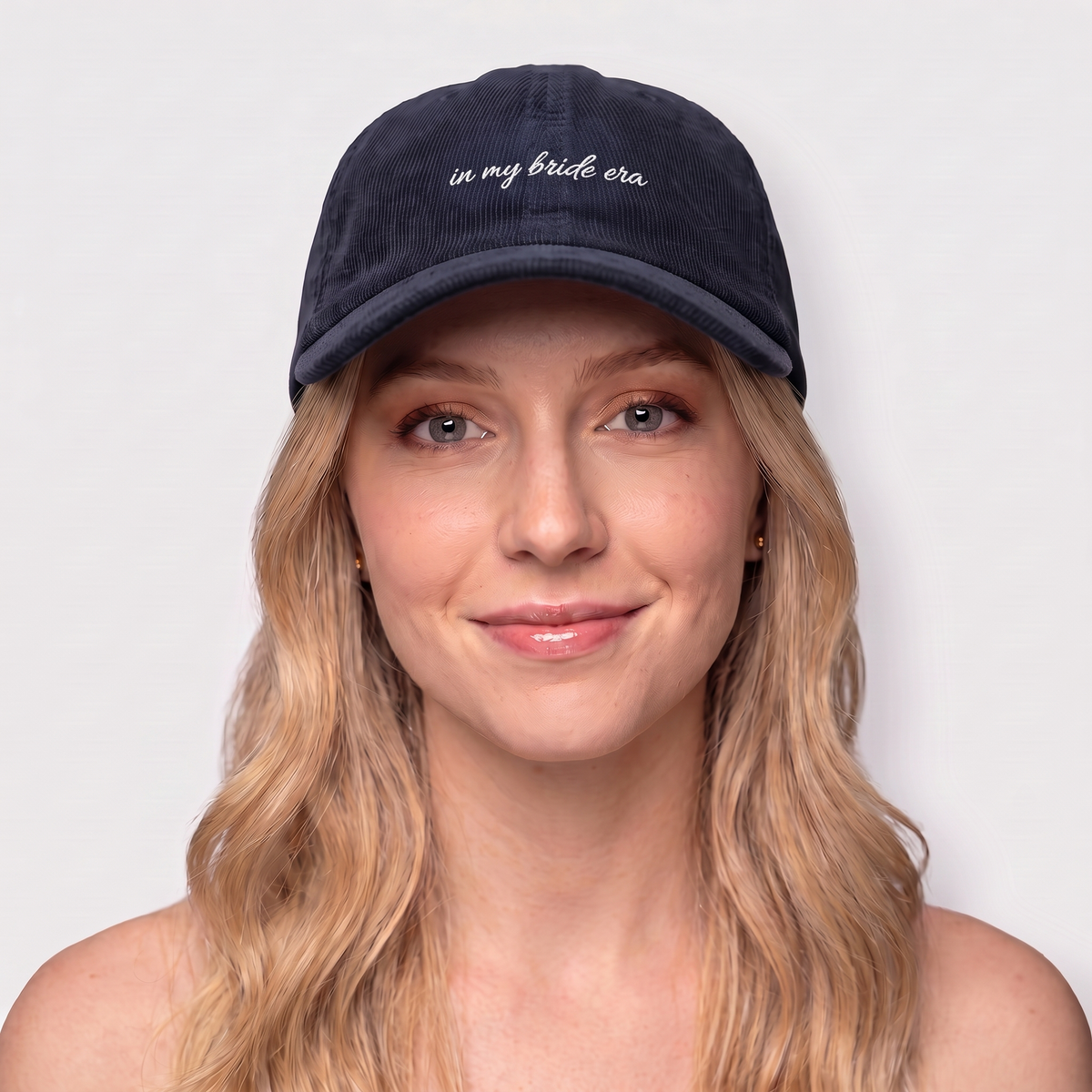 Woman wearing a navy corduroy hat embroidered 'in my bride era' — Taylor Swift Eras-inspired bachelorette cap