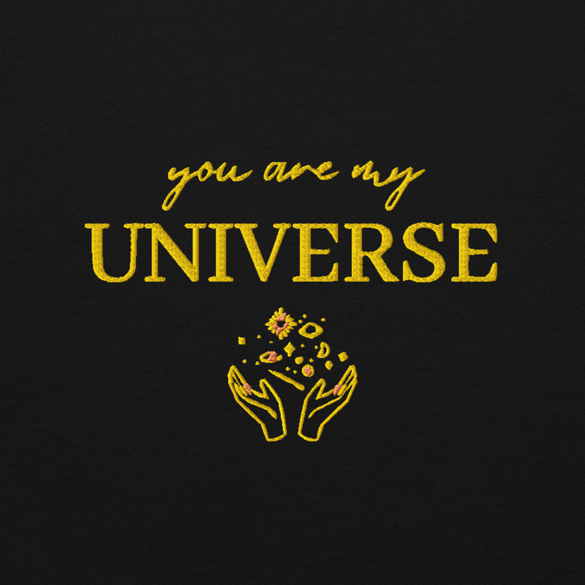 Black crewneck sweatshirt featuring yellow typography that reads “you are my Universe” with minimalist hands holding stars illustration -inspired by Coldplay’s hit song “My Universe”, aesthetic fan apparel for music lovers.
