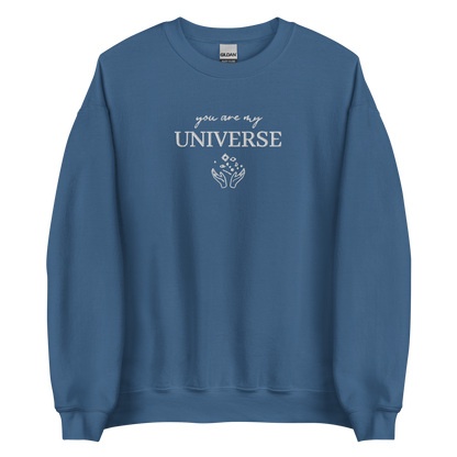Indigo blue crewneck sweatshirt featuring white typography that reads “you are my Universe” with minimalist hands holding stars illustration -inspired by Coldplay’s hit song “My Universe”, aesthetic fan apparel for music lovers.