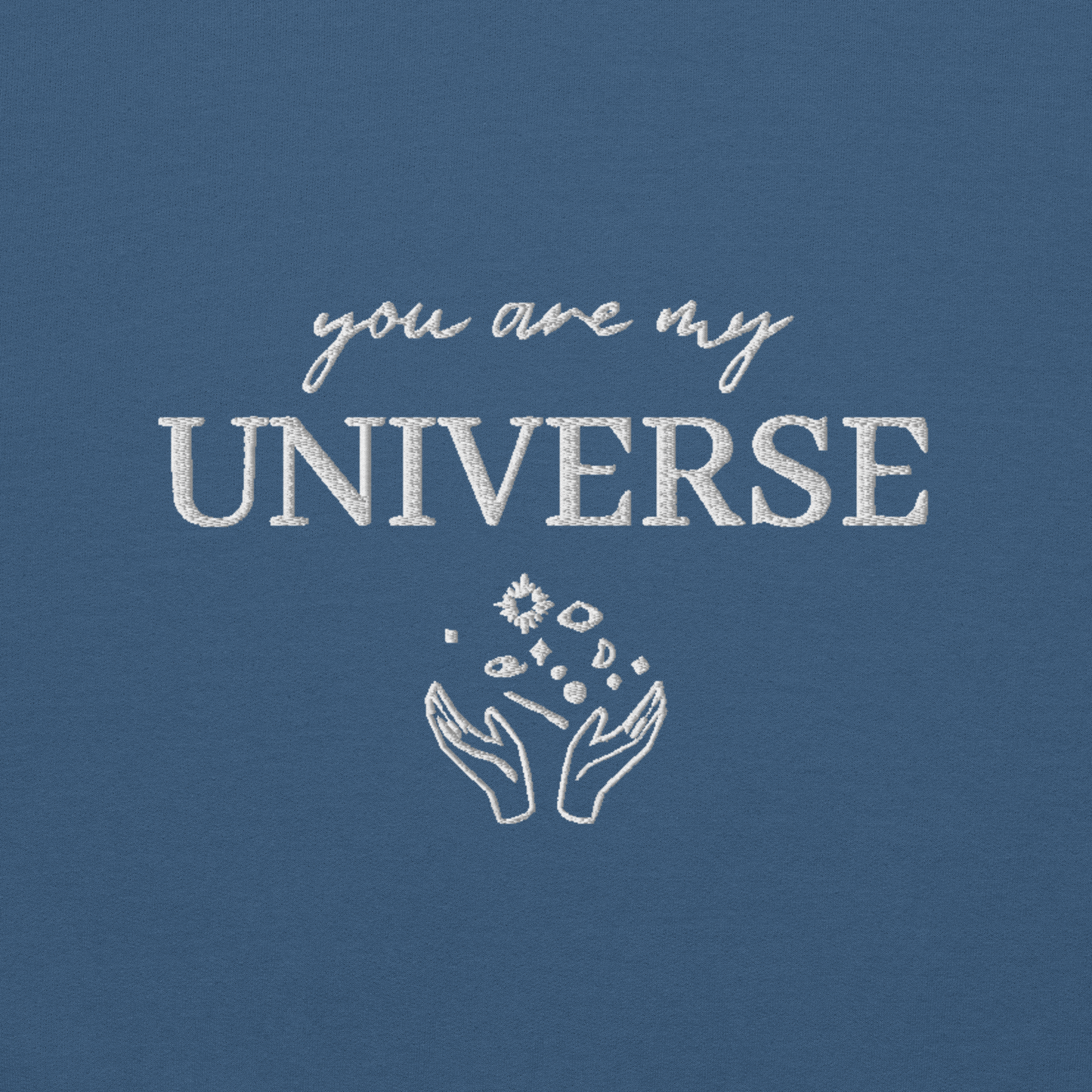Indigo blue crewneck sweatshirt featuring white typography that reads “you are my Universe” with minimalist hands holding stars illustration -inspired by Coldplay’s hit song “My Universe”, aesthetic fan apparel for music lovers.
