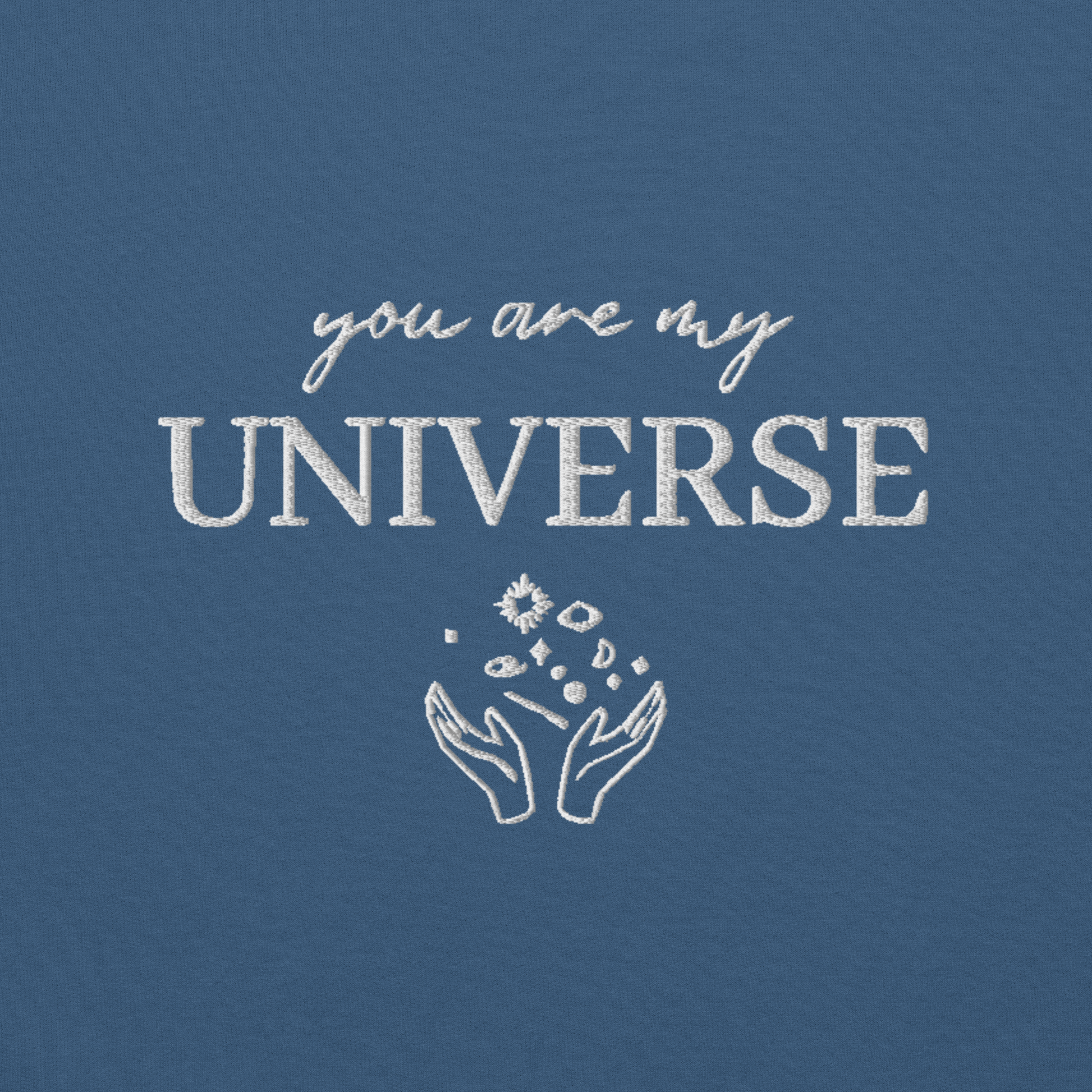 Indigo blue crewneck sweatshirt featuring white typography that reads “you are my Universe” with minimalist hands holding stars illustration -inspired by Coldplay’s hit song “My Universe”, aesthetic fan apparel for music lovers.