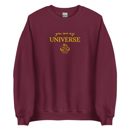 Maroon crewneck sweatshirt featuring yellow typography that reads “you are my Universe” with minimalist hands holding stars illustration -inspired by Coldplay’s hit song “My Universe”, aesthetic fan apparel for music lovers.