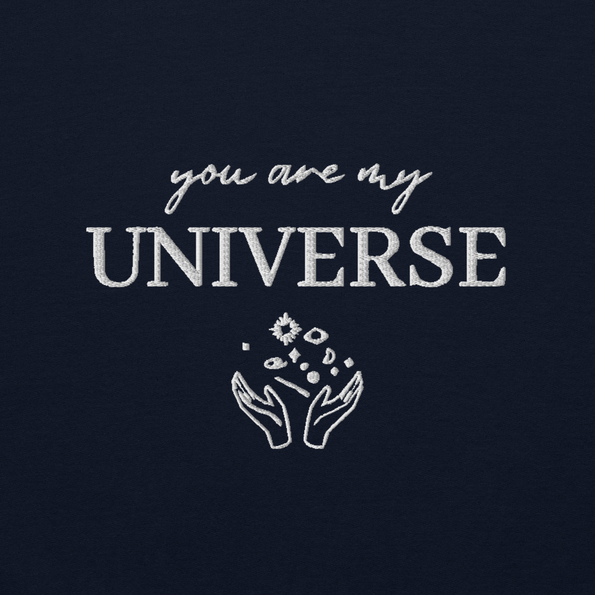 Navy crewneck sweatshirt featuring white typography that reads “you are my Universe” with minimalist hands holding stars illustration -inspired by Coldplay’s hit song “My Universe”, aesthetic fan apparel for music lovers.