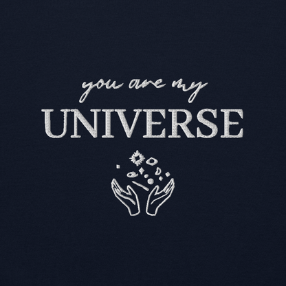 Navy crewneck sweatshirt featuring white typography that reads “you are my Universe” with minimalist hands holding stars illustration -inspired by Coldplay’s hit song “My Universe”, aesthetic fan apparel for music lovers.