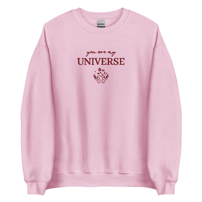 Pink crewneck sweatshirt featuring maroon typography that reads “you are my Universe” with minimalist hands holding stars illustration -inspired by Coldplay’s hit song “My Universe”, aesthetic fan apparel for music lovers.