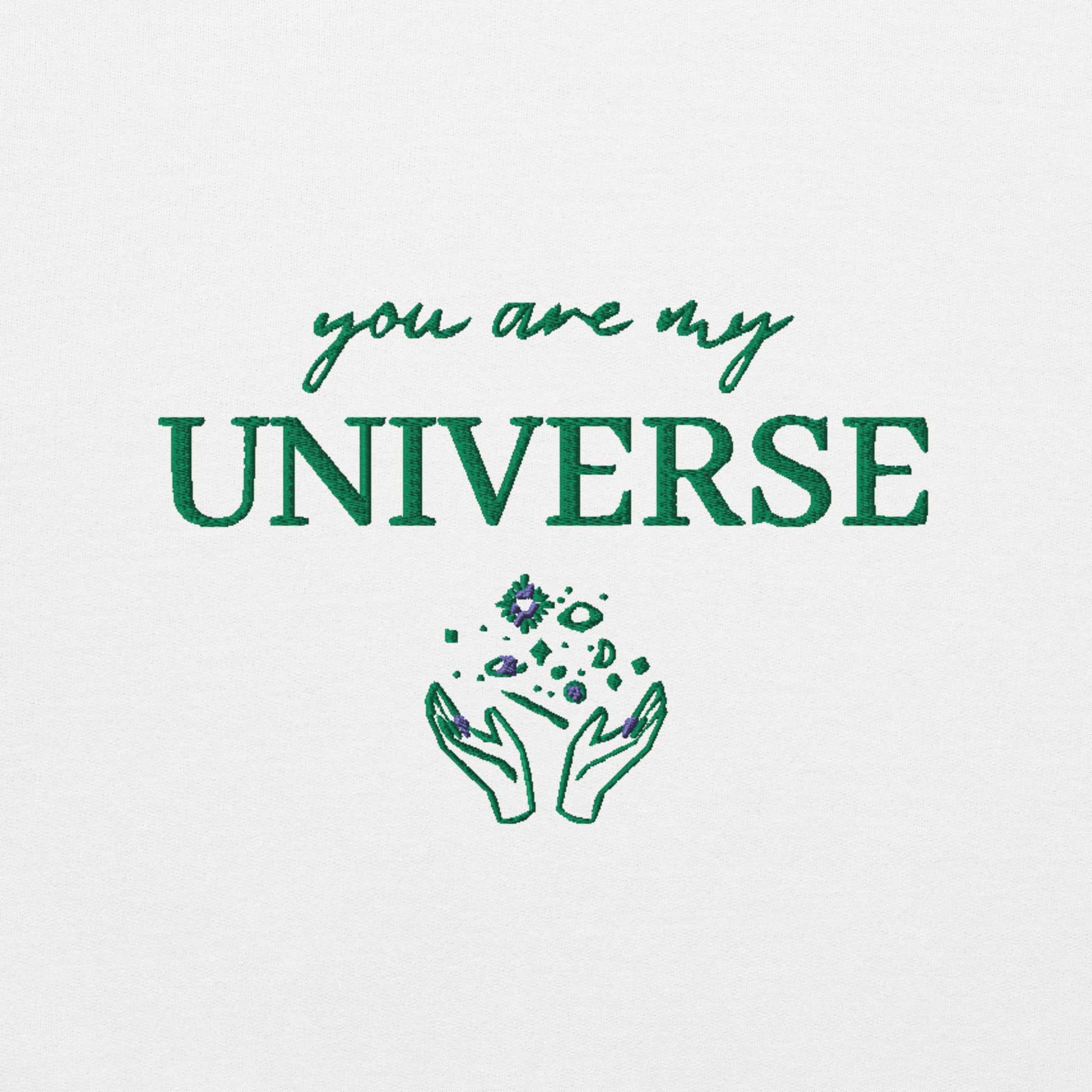 White crewneck sweatshirt featuring green typography that reads “you are my Universe” with minimalist hands holding stars illustration -inspired by Coldplay’s hit song “My Universe”, aesthetic fan apparel for music lovers.