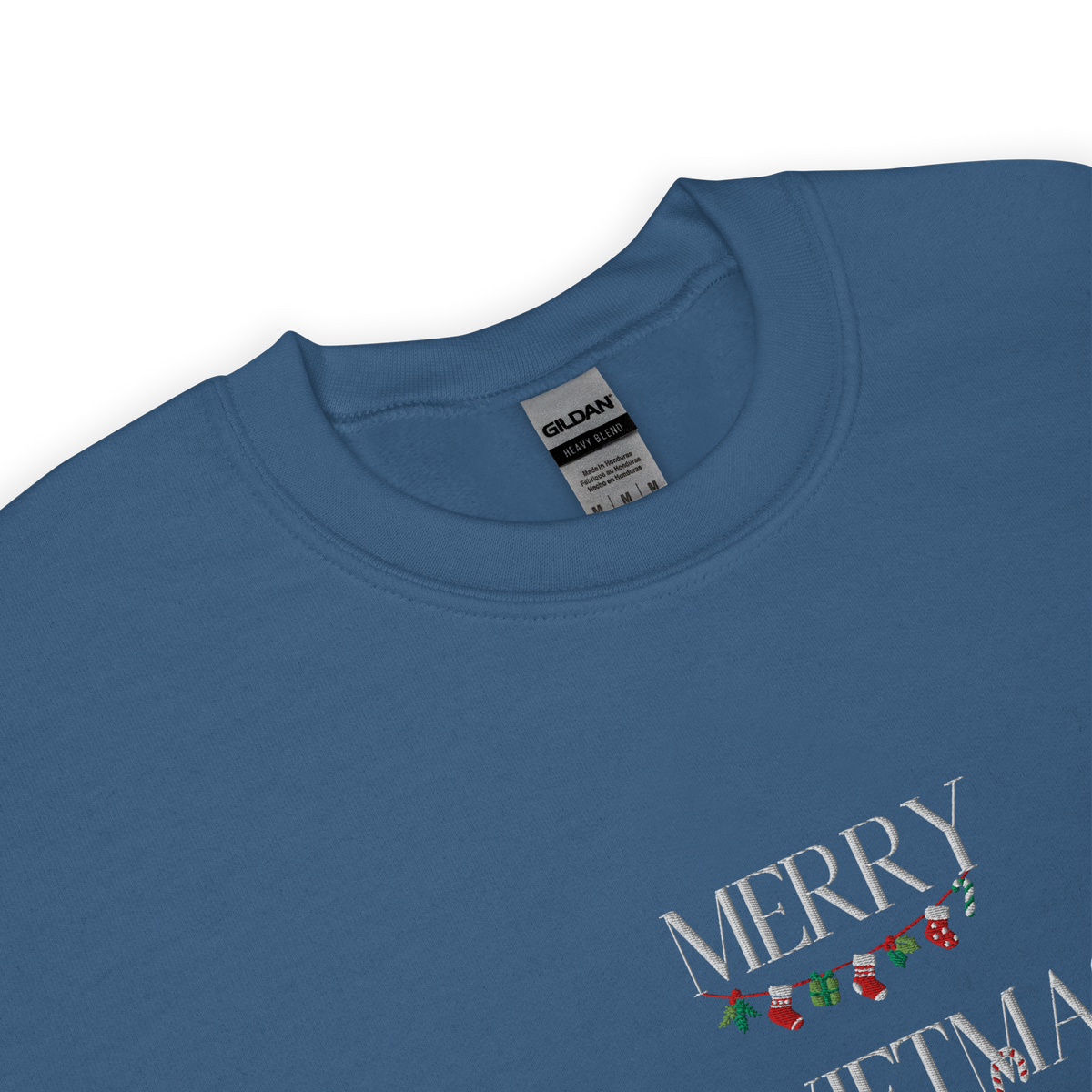 Indigo blue sweatshirt, close-up view of "Merry Swiftmas" embroidered text with a stocking garland and candy cane, holiday Taylor Swift design.
