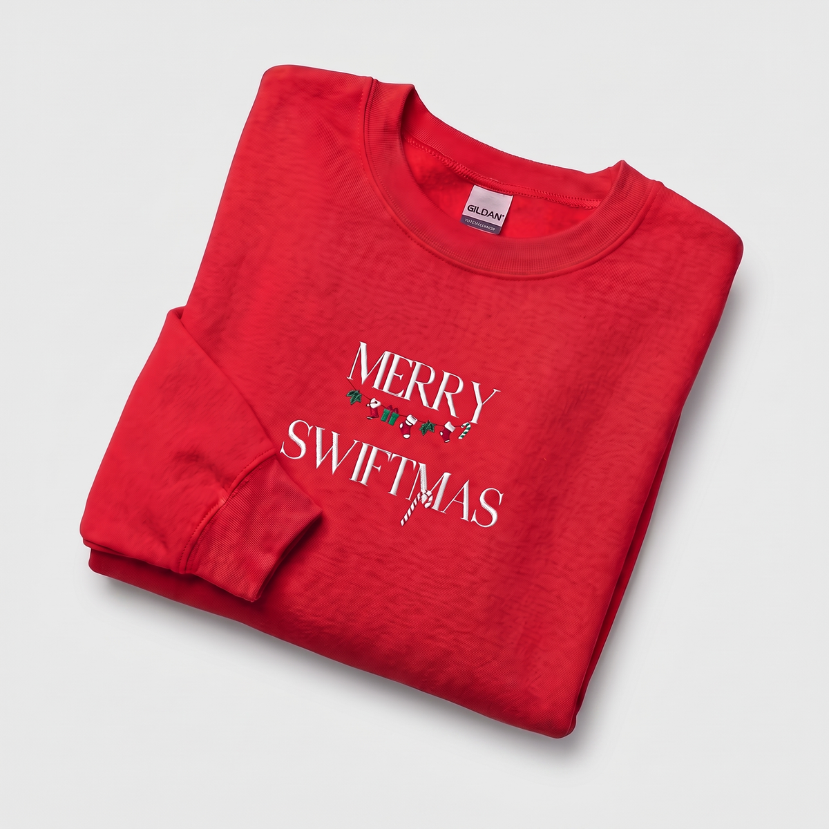 Red sweatshirt, close-up view of "Merry Swiftmas" embroidered text with a stocking garland and candy cane, holiday Taylor Swift design