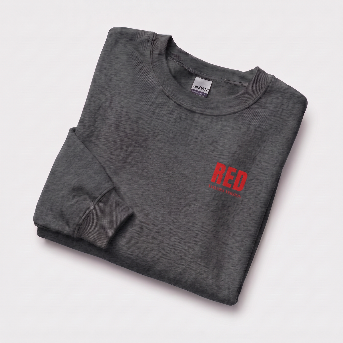 A folded dark gray crewneck sweatshirt with a red 'RED' TAYLOR'S VERSION' graphic on the left chest, displayed on a clean white background.