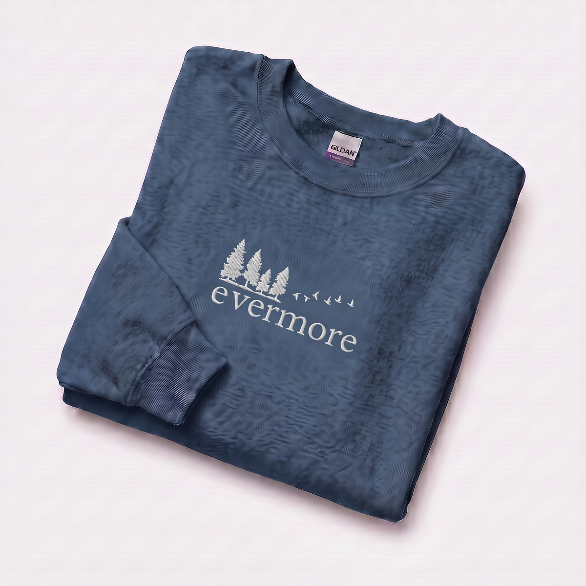 Folded indigo blue evermore era sweatshirt, Taylor Swift-inspired embroidered forest and bird design, cozy cottagecore crewneck for Swifties