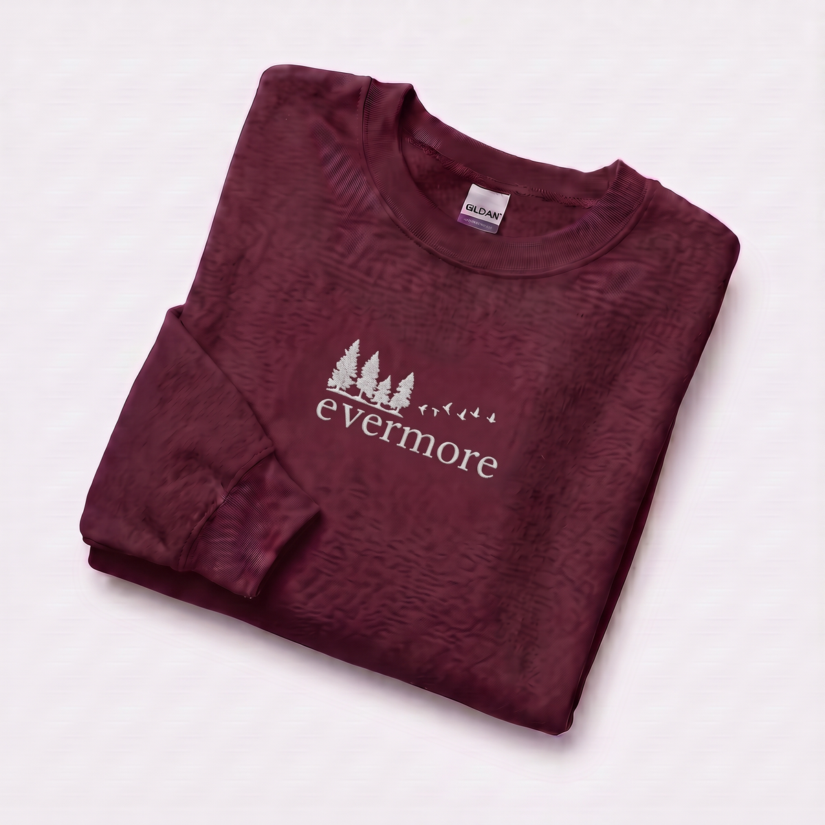 Folded maroon evermore era sweatshirt, Taylor Swift-inspired embroidered forest and bird design, cozy cottagecore crewneck for Swifties
