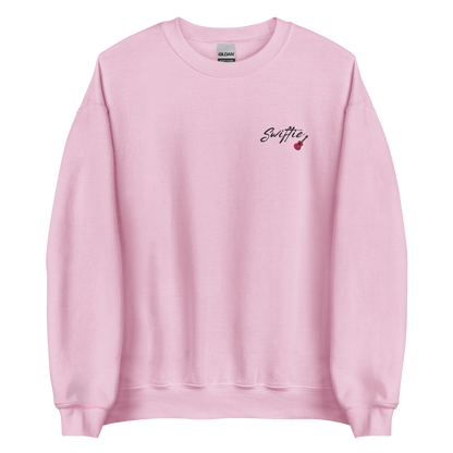 Pink crewneck sweatshirt with black “Swiftie” script and small guitar graphic on the chest, Taylor Swift inspired fan merch, cozy unisex pullover for concerts and everyday wear