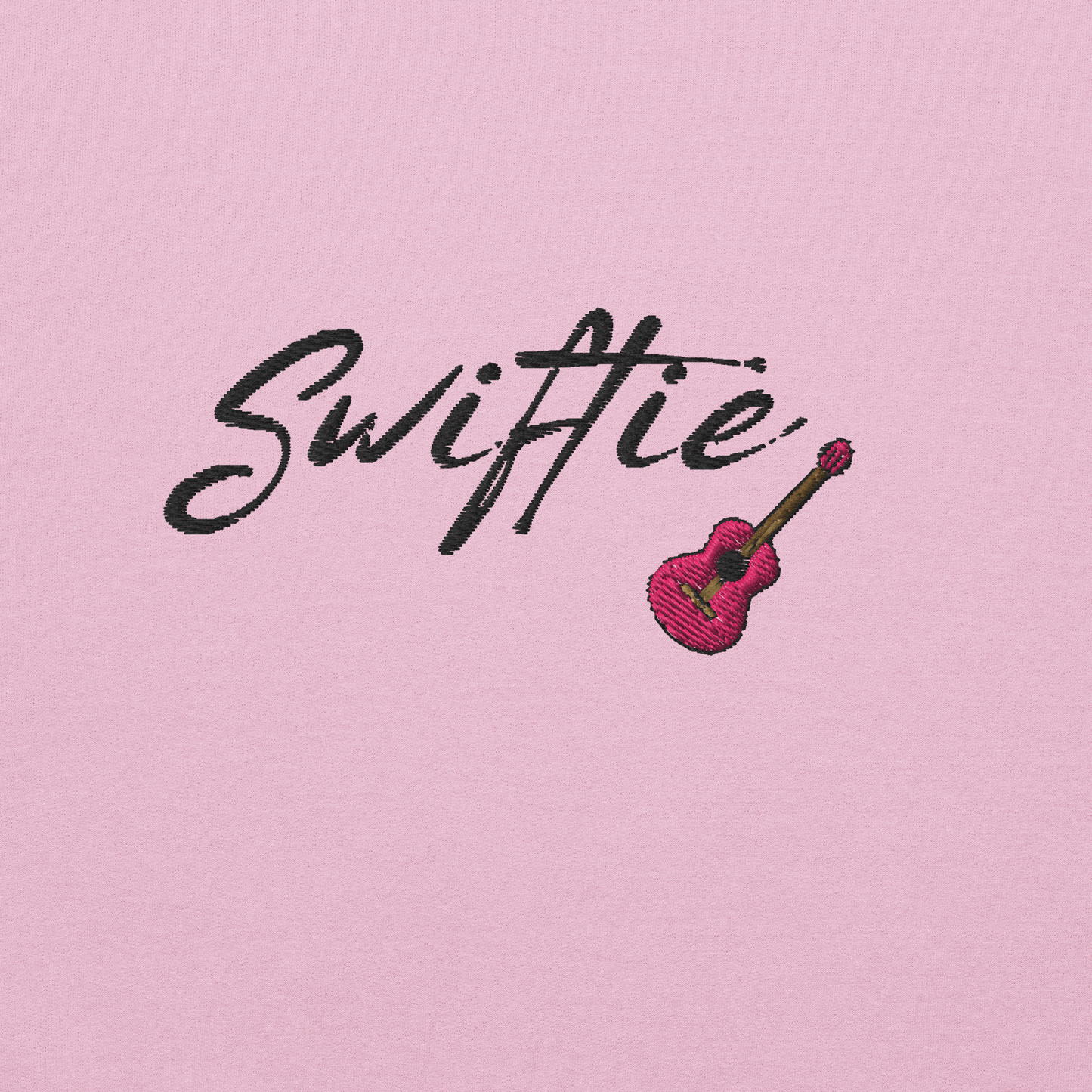 Pink crewneck sweatshirt with black “Swiftie” script and small guitar graphic on the chest, Taylor Swift inspired fan merch, cozy unisex pullover for concerts and everyday wear