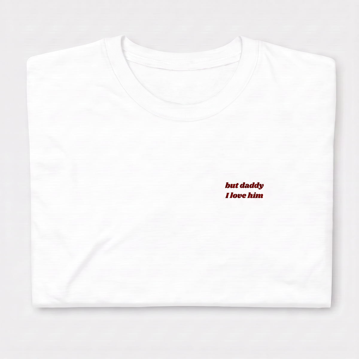 Close-up of 'but daddy I love him' embroidered in red script text on a white Taylor Swift t-shirt, Tortured Poets Department inspired design