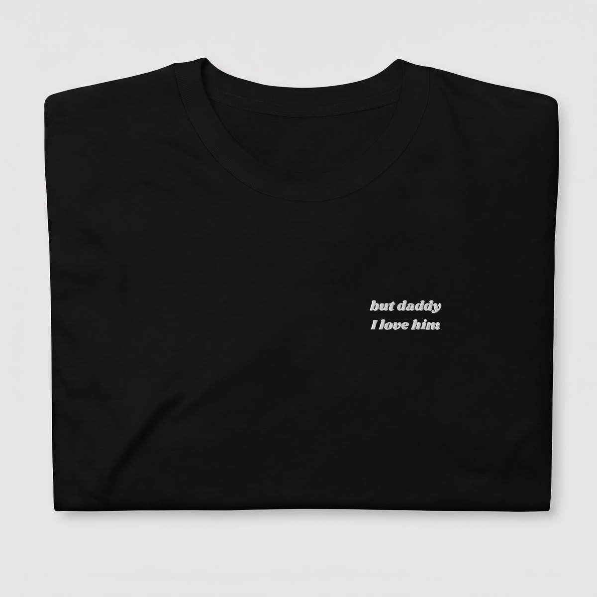 Close-up of 'but daddy I love him' embroidered in white script text on a black Taylor Swift t-shirt, Tortured Poets Department inspired design