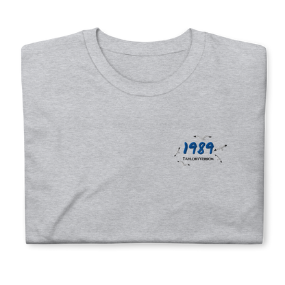 Grey Taylor Swift 1989 (Taylor’s Version) t-shirt featuring a minimalist chest print with blue “1989” lettering and seagull details. Soft unisex tee inspired by Taylor Swift’s 1989 album, perfect for Swifties, concert outfits, and casual pop music streetwear looks