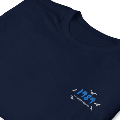 Navy Taylor Swift 1989 (Taylor’s Version) t-shirt featuring a minimalist chest print with blue “1989” lettering and seagull details. Soft unisex tee inspired by Taylor Swift’s 1989 album, perfect for Swifties, concert outfits, and casual pop music streetwear looks