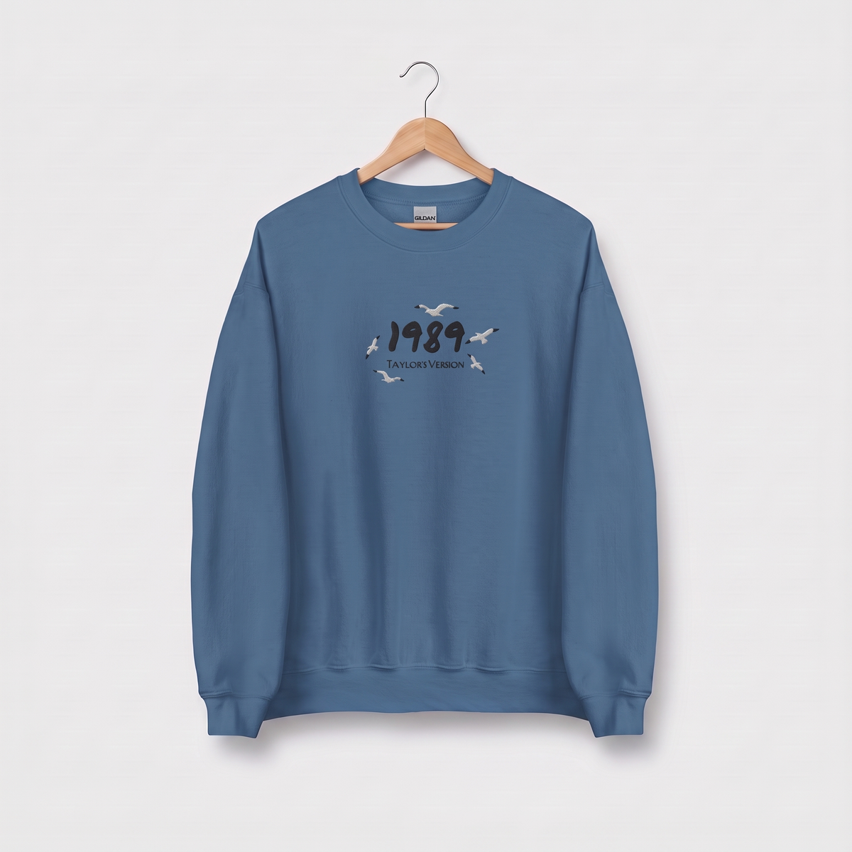 Indigo blue sweatshirt with "1989 (Taylor's Version)" embroidered text with flying seagulls