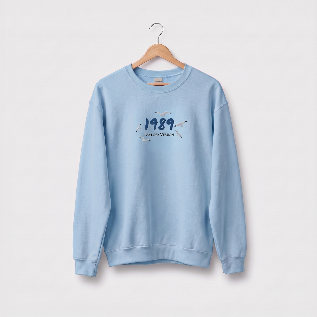 Light blue sweatshirt with "1989 (Taylor's Version)" embroidered text with flying seagulls